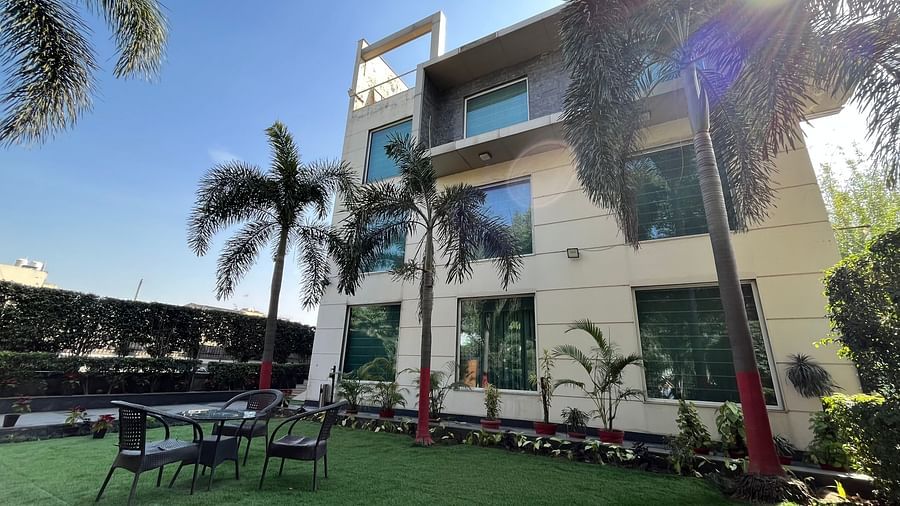 facade view of Yuhi Mansions surrouded by green coconut trees and a beautiful lawn outside the building that showcases tea-table and chairs for enjoying the view2