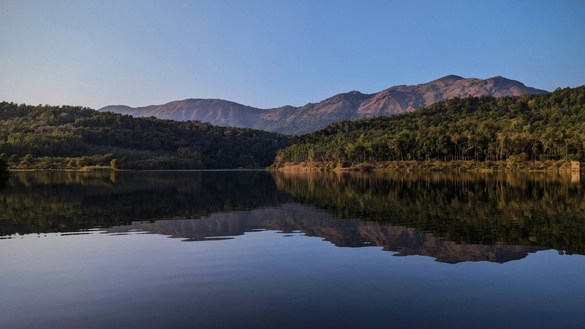 An view of a lake in Chikmagalur with the reflection of the hills in the distance on the waterbody.