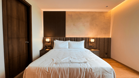 Front view of the double bed with ample of natural light coming from the window at Executive Room at F Hotels, Bengaluru.