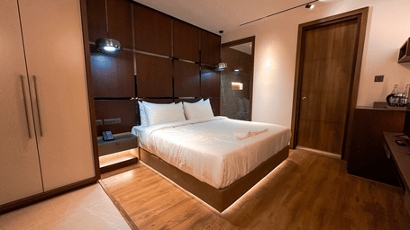 Full view of a plush double bed at the Superior Room with wooden flooring at F Hotels, Bengaluru.