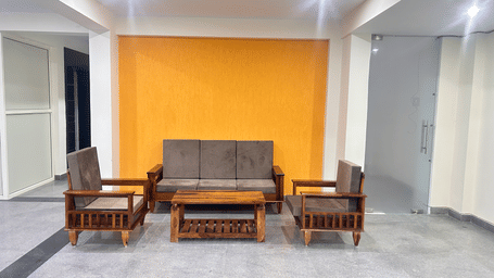 Seating area of Lime Tree Hotels & Service Apartment Private Limited featuring an orange accent wall and wooden armchairs.