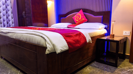 Hotel room with a bed, red bedding accents, and dark wood headboard and side table - Luffu Club