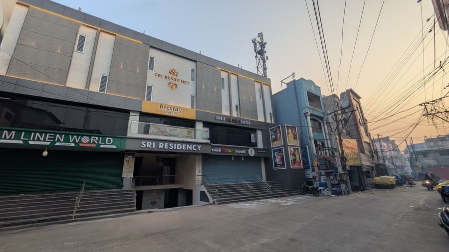 Exterior street view of Beestay Hotels with nearby shops and parked vehicles in Rajahmundry.