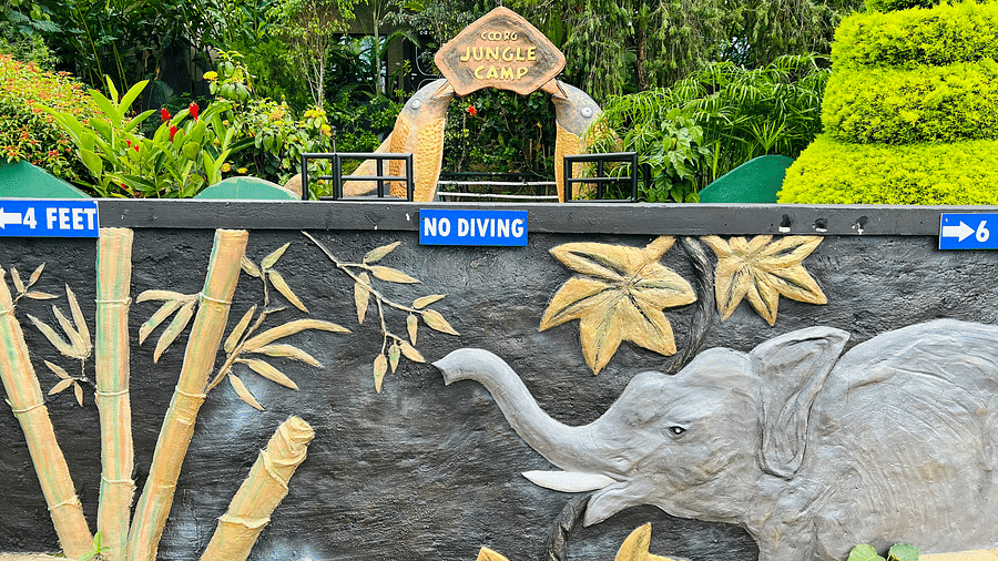 Image of a wall with the sculpture of an elephant and trees on it at Coorg Jungle Camp.
