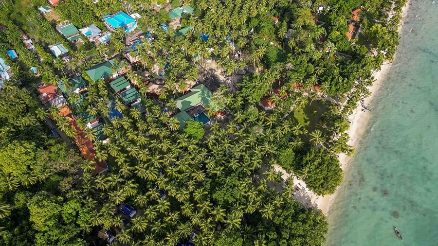  An aerial view of the tropical resort, highlighting the lush greenery and the beach area, with colourful buildings scattered among the foliage, offering a serene escape - Coral Reef Resort & Spa, Havelock