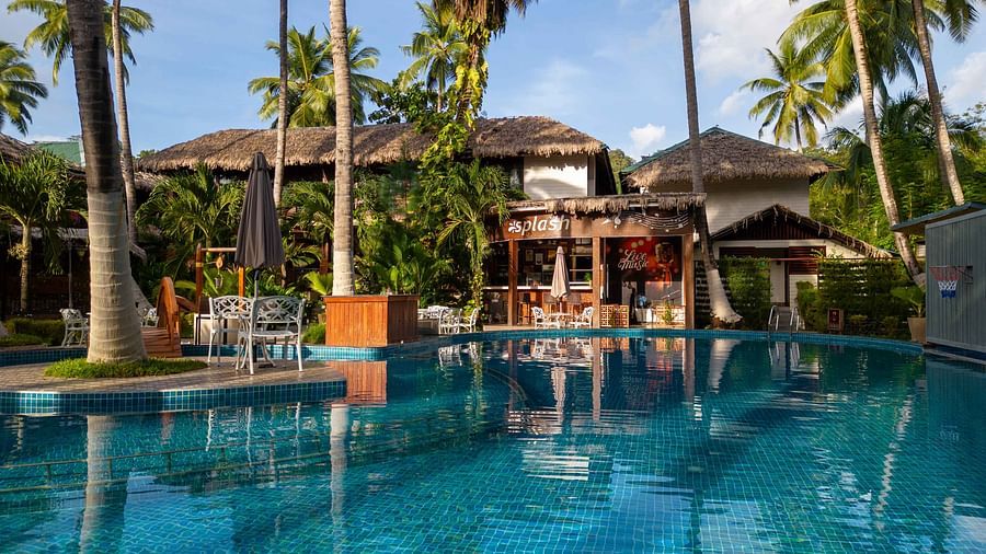  A panoramic view of a resorts outdoor pool area with tropical palm trees and well-maintained gardens surrounding the space. The setting creates a peaceful, relaxing environment - Coral Reef Resort & Spa, Havelock
