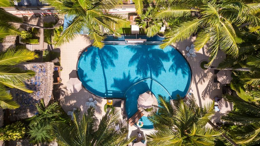  An aerial view of a pool with an intricate design, surrounded by lush foliage. The water in the pool creates a relaxing blue hue amidst the tropical garden - Coral Reef Resort & Spa, Havelock