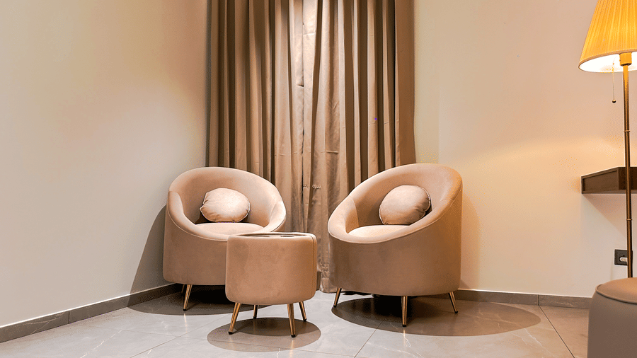2 arm chairs with a round cushion kept on each in front of a small coffee table in the living room of the Apartment Suite of F Hotels, Bengaluru.
