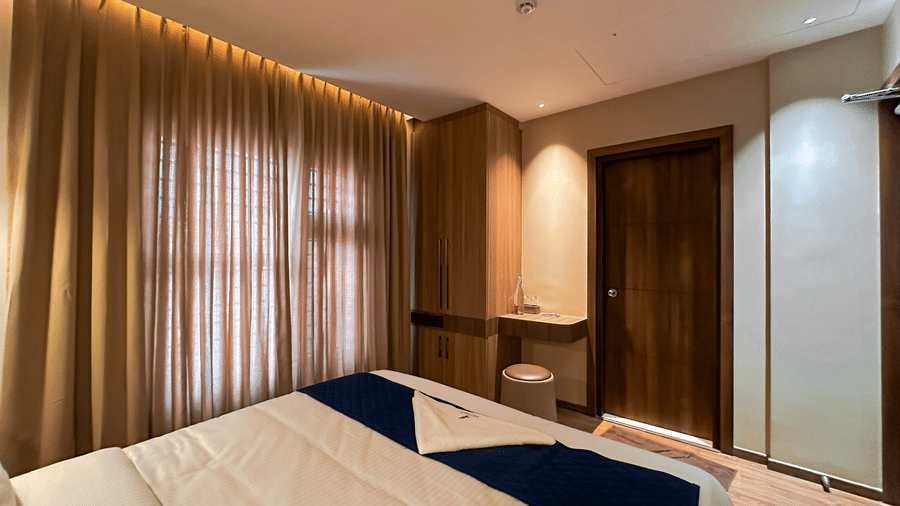 An overhead shot of the bedroom of the Apartment Suite featuring a double bed facing the wardrobe and a wooden door at F Hotels, Bengaluru.