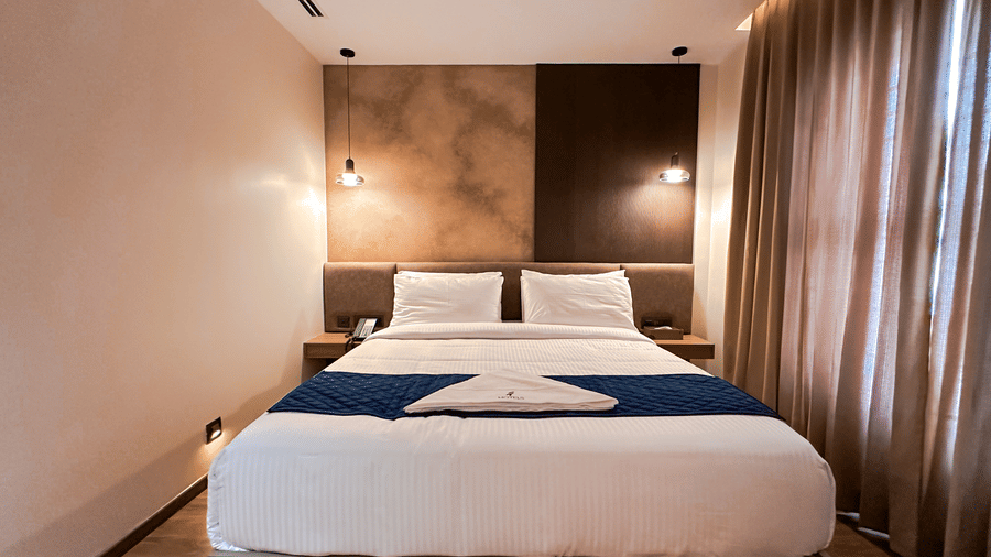 Front view of the double bed with a blue bed runner spreak over it in the bedroom of the Apartment Suite at F Hotels, Bengaluru.