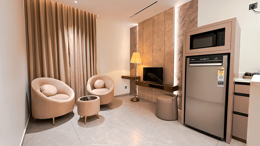 The separate living room at the Apartment Suite featuring 2 arm chairs facing the television at F Hotels, Bengaluru.