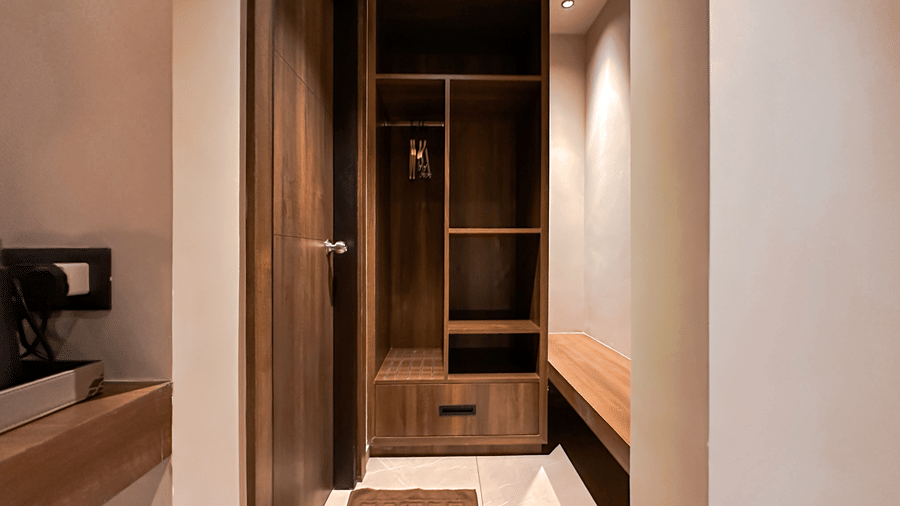 A wooden wardrobe with multiple sections in a corner of the Deluxe Room at F Hotels, Bengaluru.