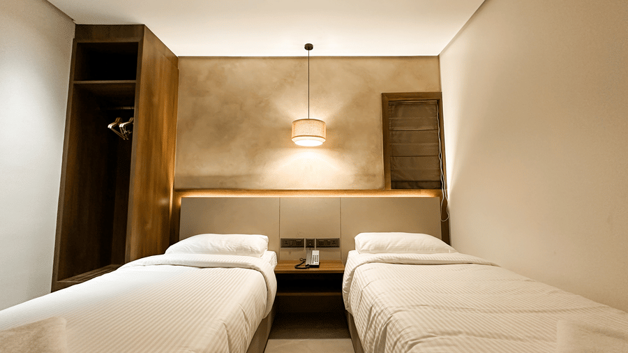Full view of the Deluxe Room at F Hotels, Bengaluru, featuring a brightly lit lamp suspended from the ceiling.