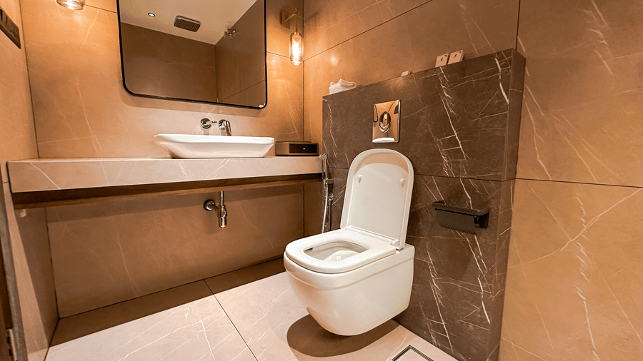 The bathroom of the Executive Room featuring a commode beside the wash basin at F Hotels, Bengaluru.