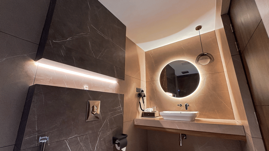 The vanity area in the bathroom at the Executive Room with a backlit round mirror above the wash basin at F Hotels, Bengaluru.