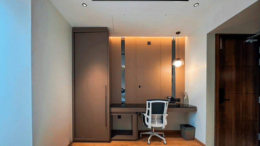 Front view of the work station at the Executive Room featuring an office chair and a light fixture suspended from the ceiling in the corner at F Hotels, Bengaluru.