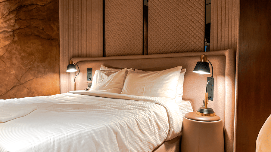 Close up of the plush king size bed in the bedroom of the Honeymoon Suite with illuminated bedside lamps on either side of it at F Hotels, Bengaluru.