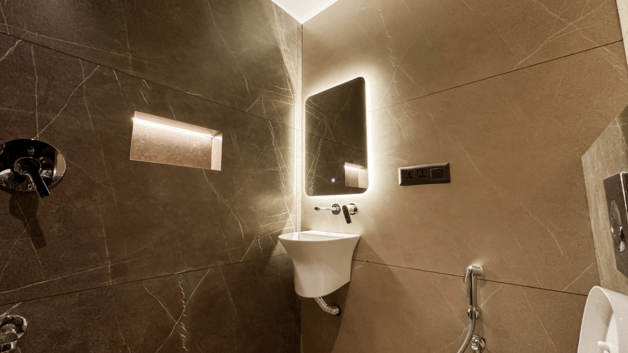 The wash basin in the common bathroom along with a rectangular backlit mirror at F Hotels, Bengaluru.