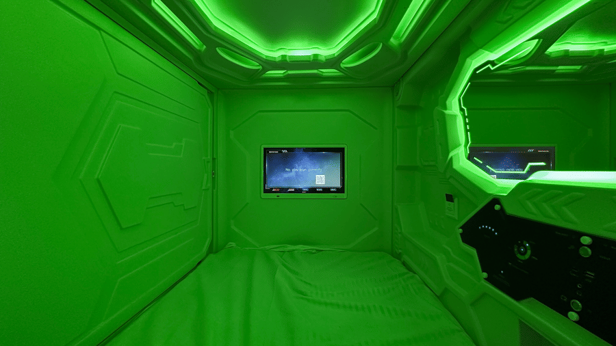 A small television screen place inside the private pod illuminated with green lighting at F Hotels, Bengaluru.