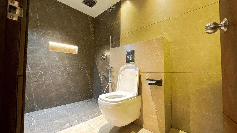 A commode with an open flap beside the shower area at the Superior Room at F Hotels, Bengaluru.