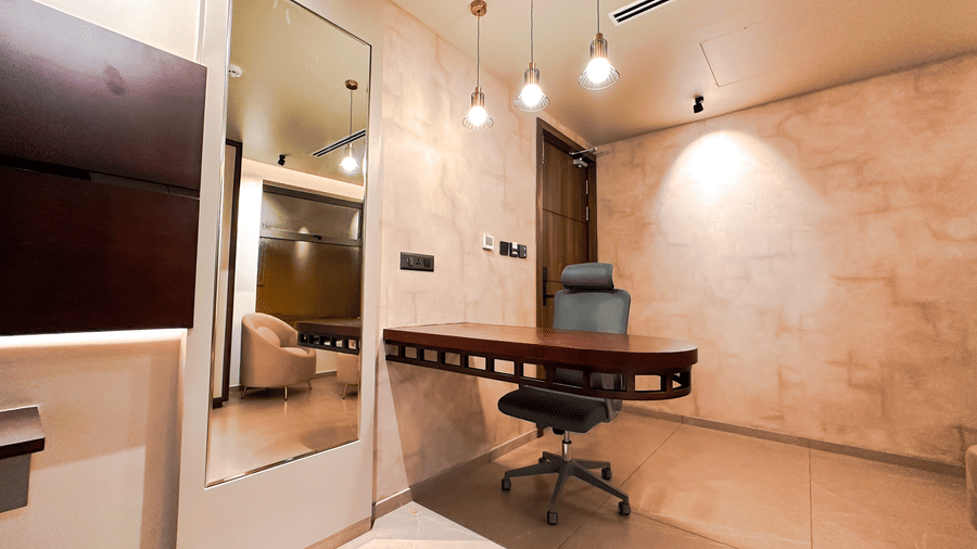 A full-length mirror beside the wall-mounted desk along with an office chair in the Superior Room at F Hotels, Bengaluru.