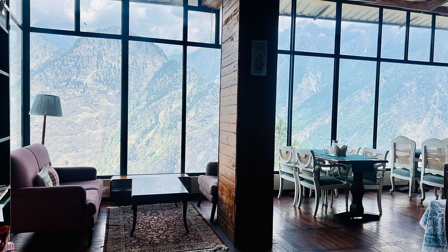 Cozy interior of a mountain lodge dining area with stylish furnishings and mountain views  | Faraway Cottages, Auli