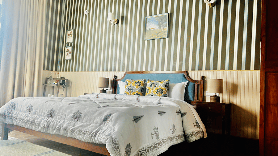 Bedroom at Faraway Cottages, Auli, with striped accent wall, double bed, bedside lamps, and wooden furniture.