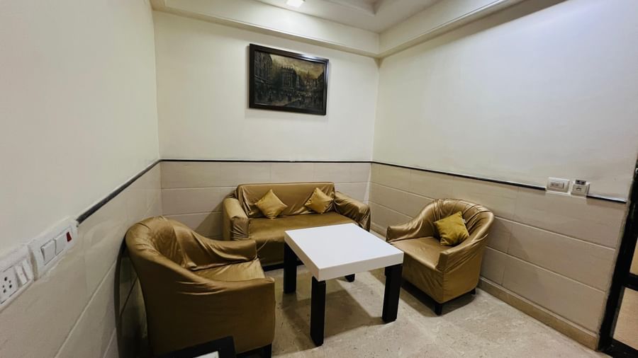 A cozy hotel suite with a brown sofa, a white coffee table, and a painting on the wall, creating a comfortable ambiance. | Suite | Hotel Aadhar
