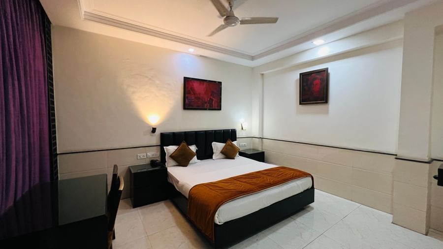 Hotel room featuring a comfortable bed, bedside table, and curtains | Deluxe Room | Hotel Aadhar