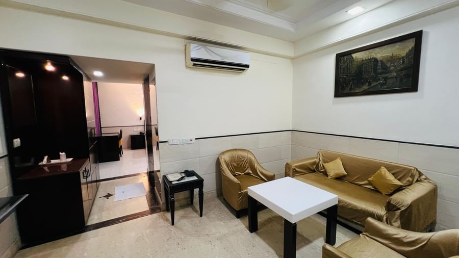 A serene hotel suite with a neatly made bed and wooden flooring, providing a calm and pleasant environment. | Suite | Hotel Aadhar