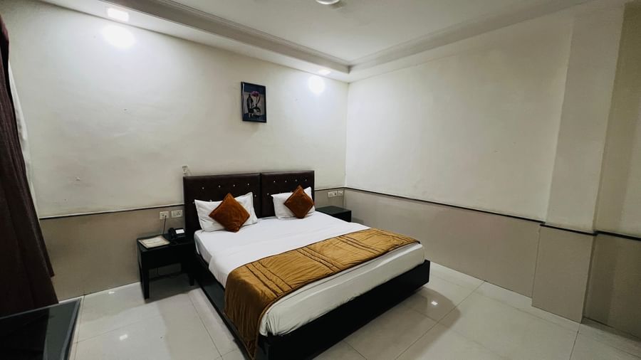 A compact hotel room with a bed and simple, functional furnishings