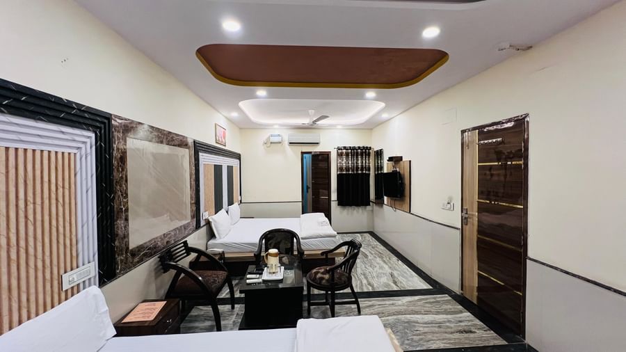 A spacious hotel room with multiple beds and a dining table, ideal for families or groups. | Family Room | Hotel City Palace DX