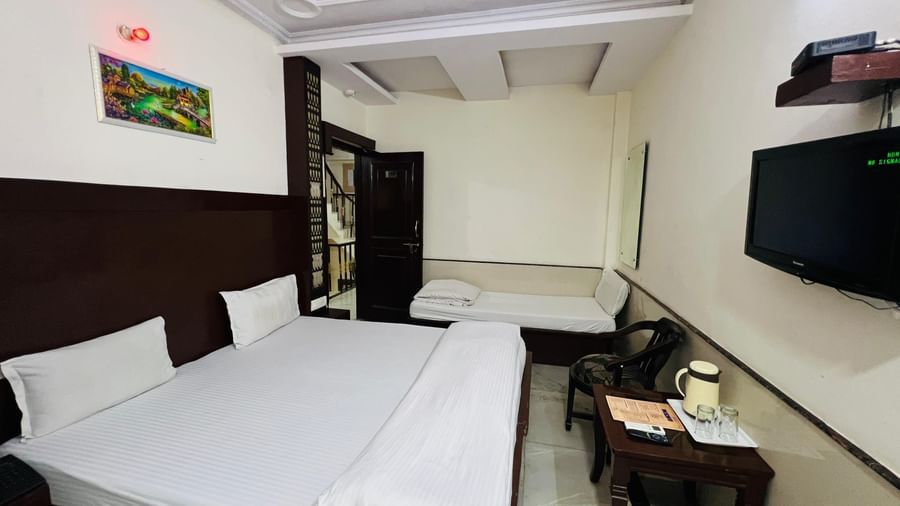 A well-furnished hotel room featuring a large bed, a sofa, and a TV, providing ample space and amenities for a relaxing stay. | Super Deluxe Room | Hotel City Palace DX