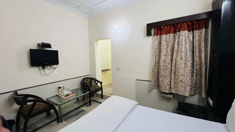 A functional standard room with a bed, a TV, and two chairs with a small table, providing essential comforts for guests at Hotel City Palace DX.