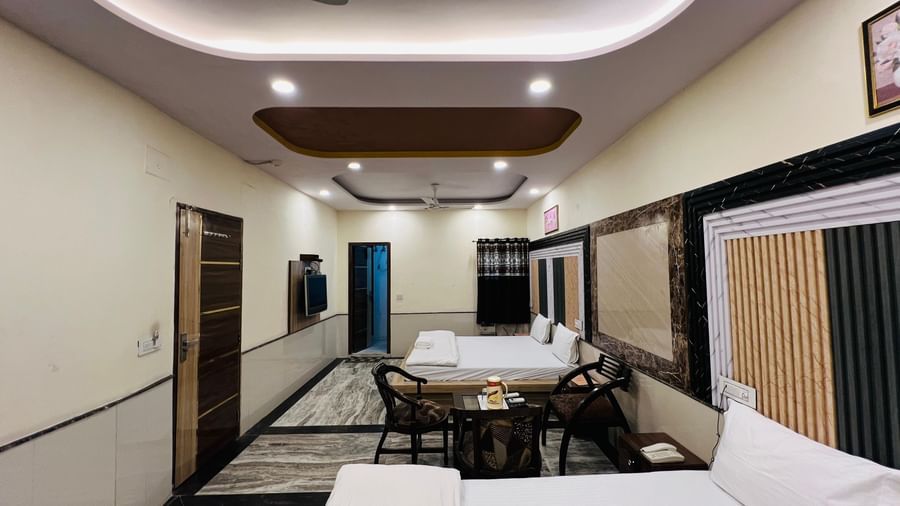 A hotel room with multiple beds and a dining setup, perfect for communal meals and relaxation. | Family Room | Hotel City Palace DX