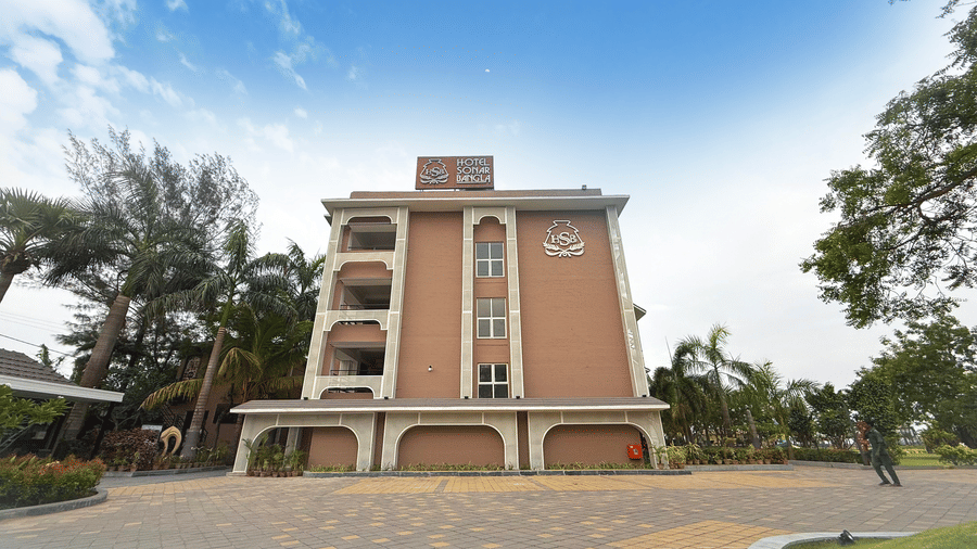 External view of Hotel Sonar Bangla in Kolaghat, showcasing its multi-storey building, and spacious driveway that is surrounded by trees.