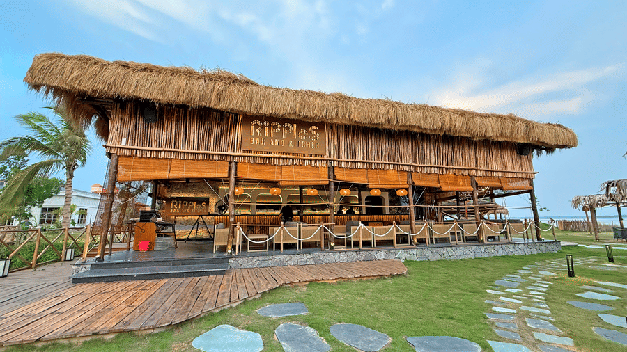 Exterior of Ripples Cafe and Bar, seen with a straw roof, stone pathway outside, at Hotel Sonar Bangla, Kolaghat.