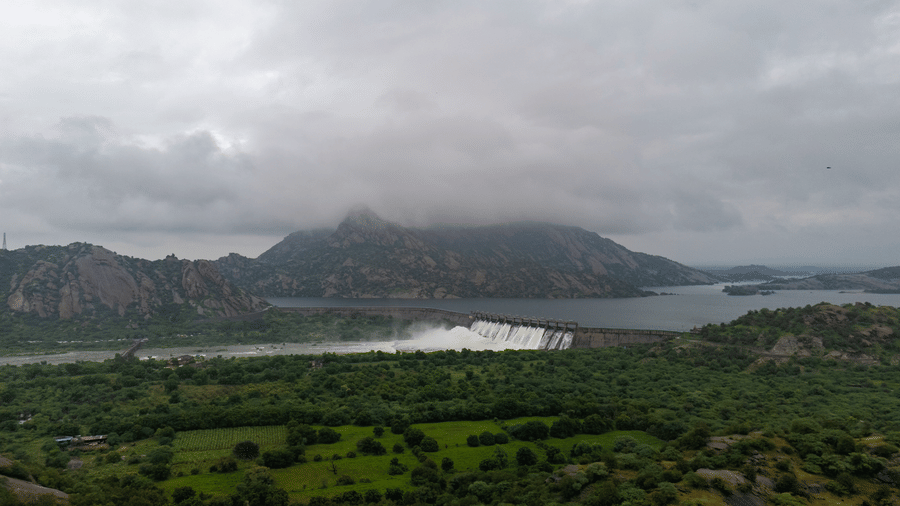  A wide landscape view on an overcast day showing a lush green valley leading toward distant, misty mountains and a calm lake.