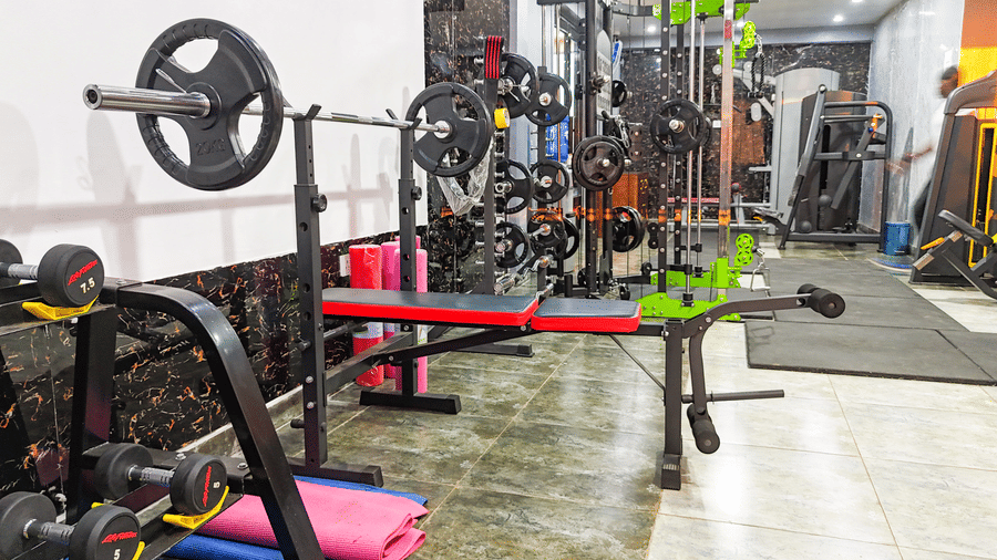 Interior view of a gym with weight racks, barbells, and exercise equipment - Luffu Club