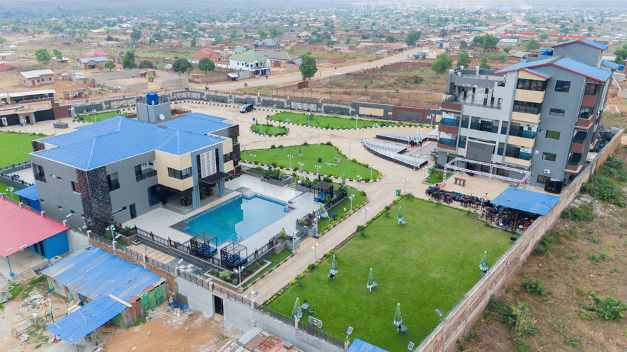 Wider aerial view of a building complex with a swimming pool, showing the surrounding neighbourhood - Luffu Club