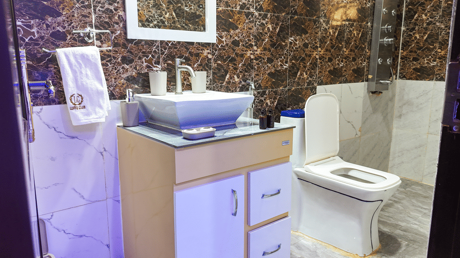 Modern bathroom interior with a wooden vanity, sink, water closet, and textured wall finish - Luffu Club