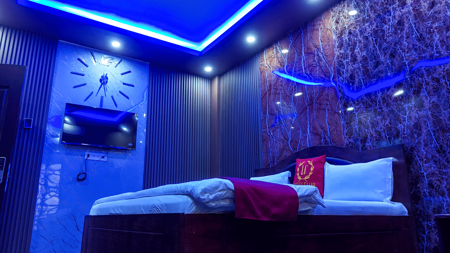Hotel room featuring a bed, wall-mounted TV, and dark, textured walls with blue accent lighting - Luffu Club