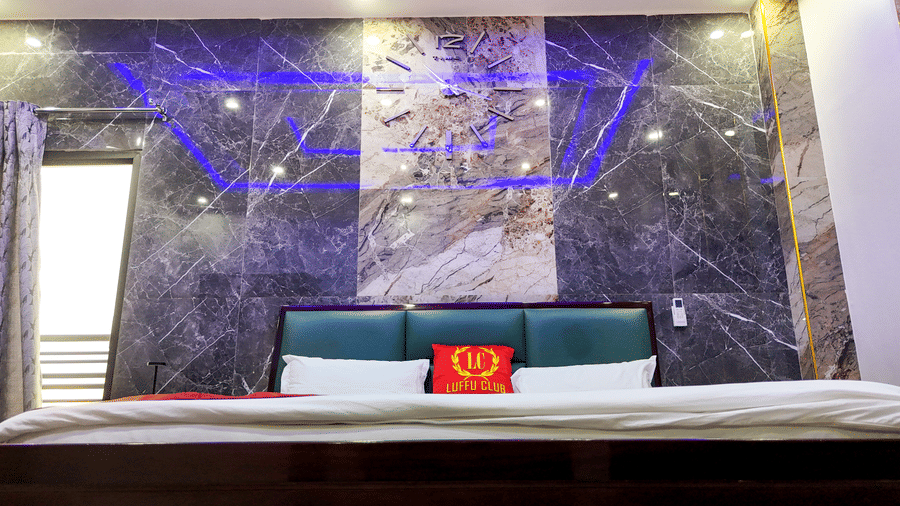 Close-up view of a hotel bed against a dark marble-style wall with blue accent lighting - Luffu Club