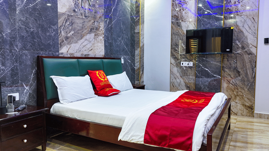 Room with a bed, red accents sheets, and marble-style wall panelling - Luffu Club