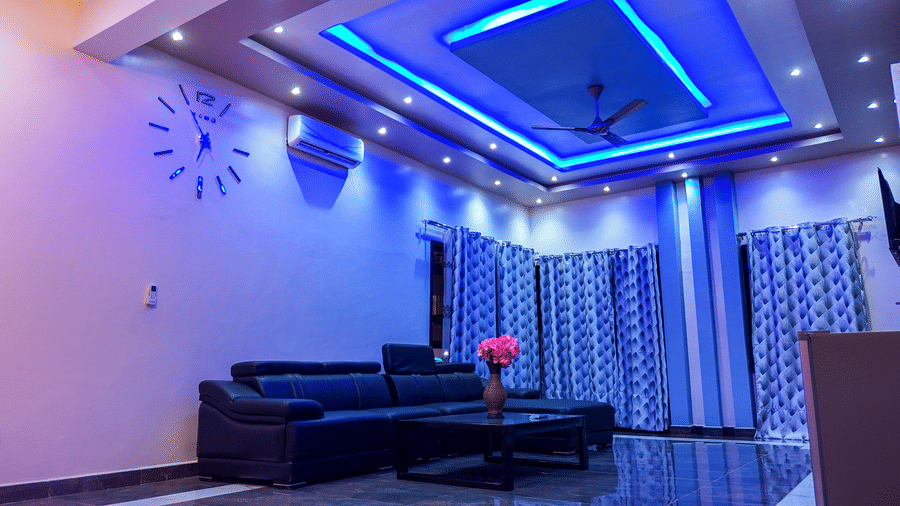 Spacious living room with blue ceiling lights, sofa, and ceiling-to-floor curtains - Luffu Club