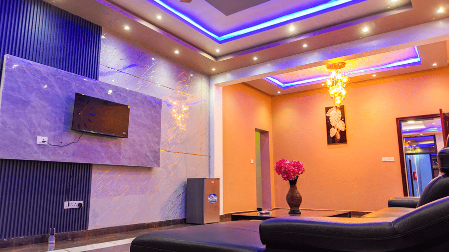 Living area with blue and purple accent lighting, a wall-mounted TV, and modern decor - Luffu Club