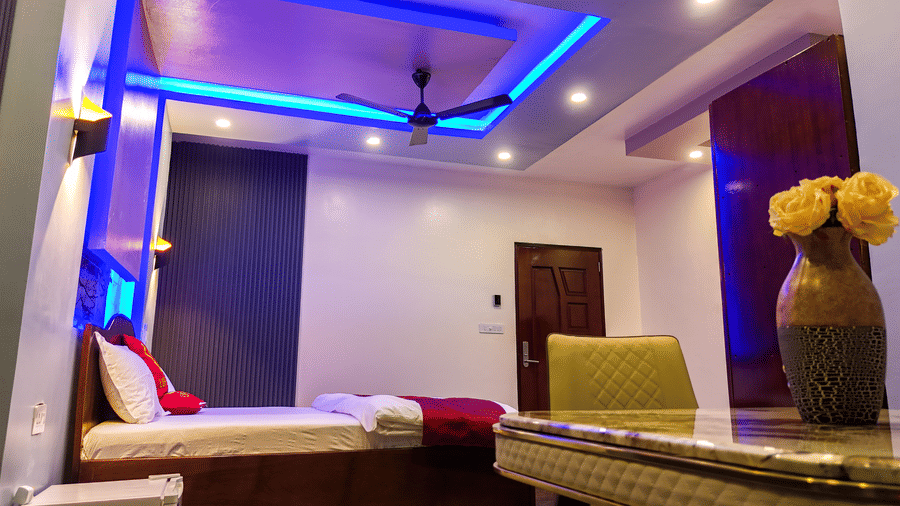 Room with blue and purple accent lighting, double bed and seating area - Luffu Club