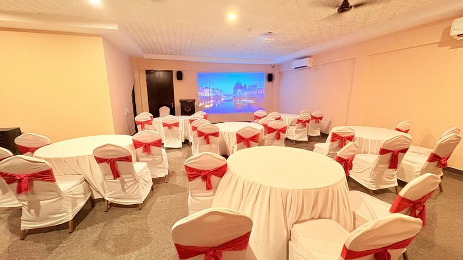 A well-lit conference hall with round tables and red chairs, ideal for meetings and events at Nazri The Verda, Arambol.