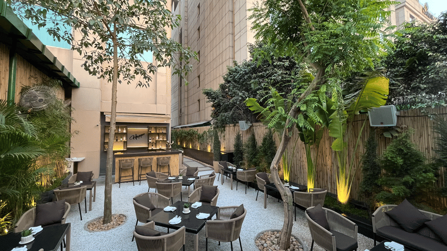 A pathway leads through Nemesia’s outdoor area with tables and chairs set for dining and a bar setup.
