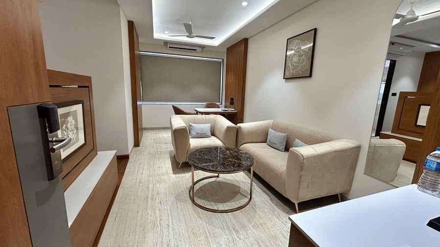 An inviting hotel suite living area with a plush cream sofa, coffee table, and flat-screen television at Pravasa Stay Bapat Square, Indore.